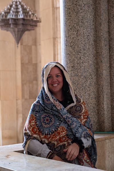 Smiling woman wrapped in a colorful shawl by stone columns Casablanca, Morocco