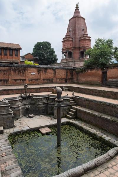 Historic brick courtyard with ancient temple tower and stone pool Bhaktapur, Nepal