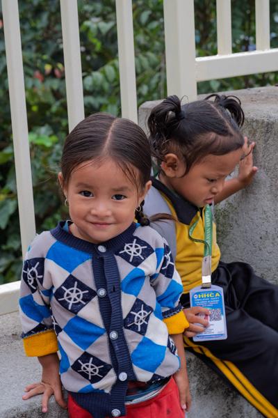 Two Young Children by a Railing with School Badge in Nepal Budhanilkantha, Nepal