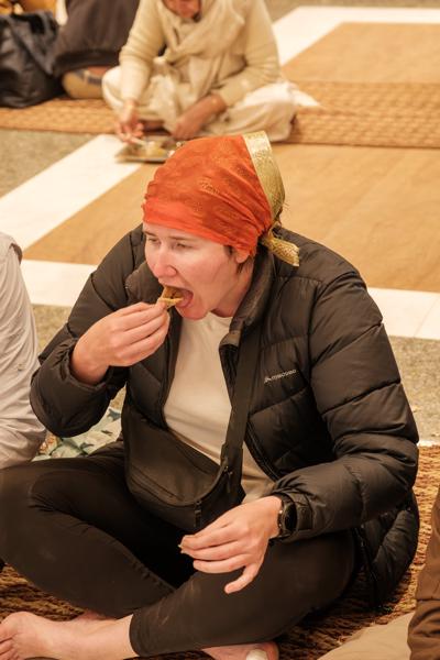 Woman Eating Prasad on Carpeted Floor in Old Delhi Delhi, India