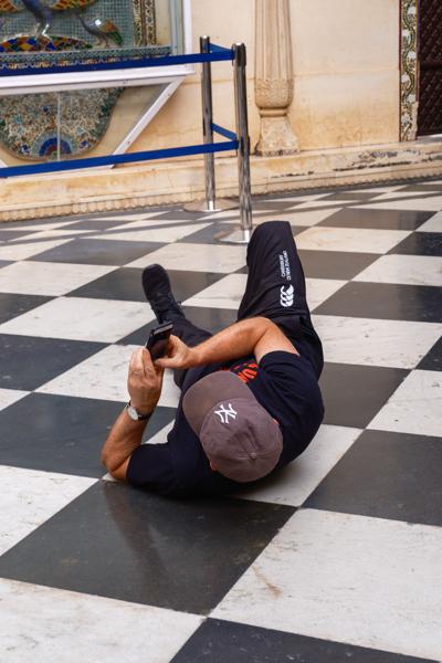 Visitor Taking a Low-Angle Photo on a Checkered Marble Courtyard Floor, Udaipur Udaipur, India
