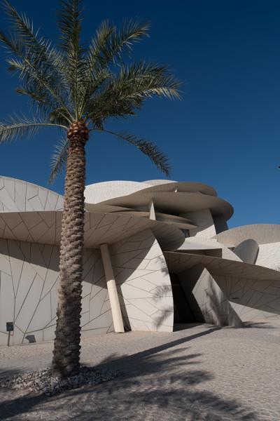 Palm tree in front of a geometric white museum exterior under a clear blue sky Doha, Qatar