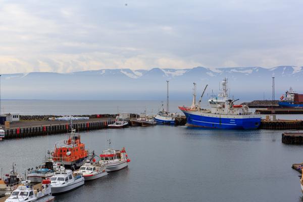 Harbor scene with blue glacier-ship and snow-capped mountains Húsavík, Iceland