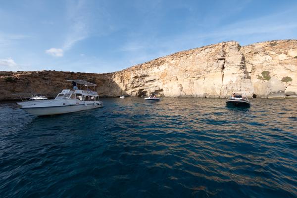 Boats anchored off limestone cliffs in Comino, Malta Għajnsielem, Malta