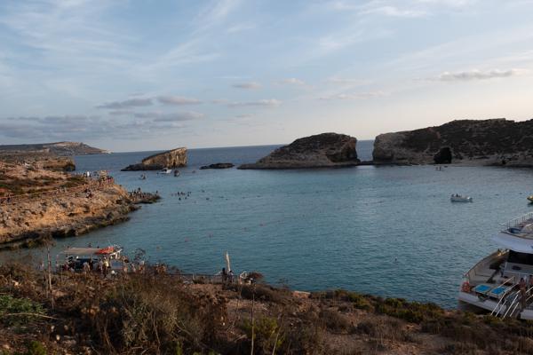 Coastal cove and boats off the Maltese shore at golden hour Gozo Region, Malta