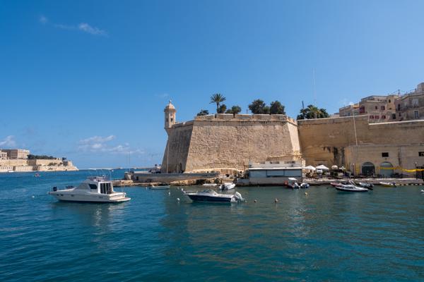 Sunny harbour beside a limestone bastion in Valletta Port Region, Malta