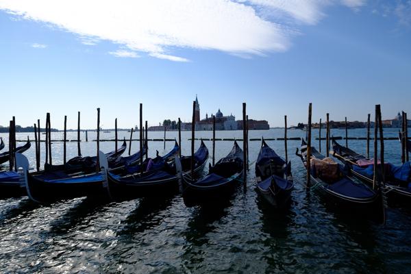 Gondolas Moored Along a Venetian Waterway with Cityscape in the Distance Venice, Italy